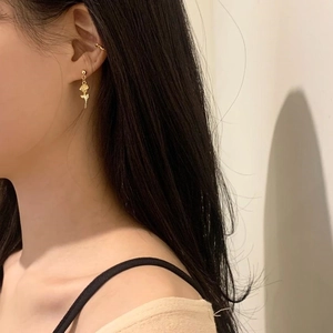 Close-up of elegant gold rose flower stud earrings worn by a model in soft lighting