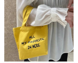 Detail of yellow canvas mini tote bag featuring ALL MY FAVORITE IN HERE text print