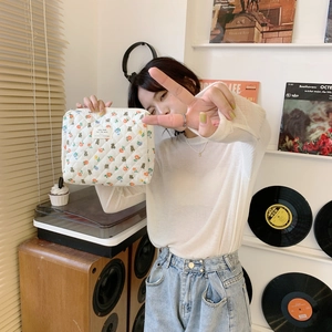 Close-up of quilted floral makeup bag with bear prints held by a model for size
