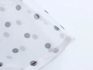 Detailansicht von weißem Chiffonstoff mit schwarzen Punkten und feiner Nahtarbeit
