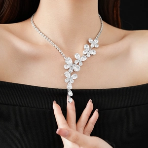 Detailed view of flower and teardrop zircon pendant necklace worn on a female model