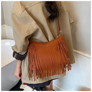 Close-up of brown matte leather shoulder bag with decorative tassels on khaki coat