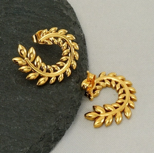 Macro detail of gold-plated laurel leaf stud earrings featuring polished C-shaped design