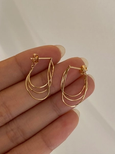 Close-up of golden multi-layered geometric tassel earrings with a sleek metallic finish