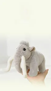 Close-up of a small grey plush mammoth toy with long white tusks and soft fur texture