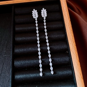 Détail de boucles d'oreilles pendantes feuilles en argent et zircon sur velours noir