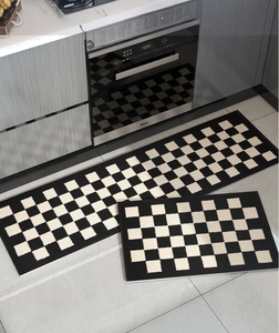 Detail view of two-piece black and white checkered woven kitchen mats on grey floor
