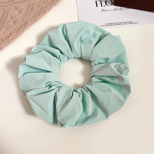 Detailed view of a soft light green ruffled scrunchie with a smooth fabric texture