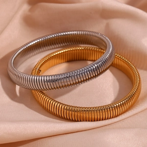 Gros plan de bracelets chaîne serpent de 10 mm en or et argent sur un tissu satiné champagne