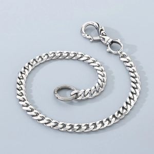 Macro detail of silver stainless steel Cuban chain featuring a skull swivel spring clasp