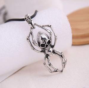 Detail shot of vintage silver skull spider pendant on a rustic wood and white fabric background