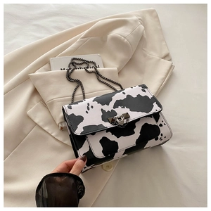 Detalle del bolso bandolera con estampado de vaca, cierre metálico y cadena de hombro