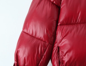 Detail shot of shiny red padded jacket showing quilted fabric texture and sleeve stitching