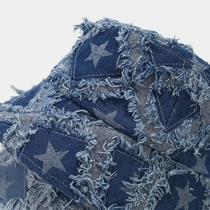 Detailed macro view of distressed star pattern on blue denim bucket hat with frayed edges