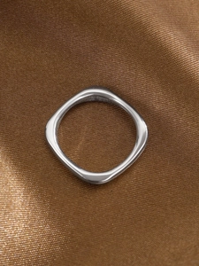 Detailed macro view of silver geometric stainless steel ring on silk fabric
