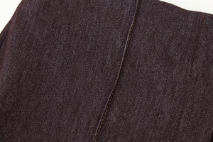 Gros plan détaillé du tissu denim foncé avec coutures jaunes et texture sergé