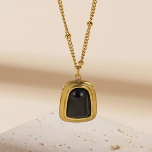 Elegant gold necklace with a square black cat eye stone pendant on a textured stone base
