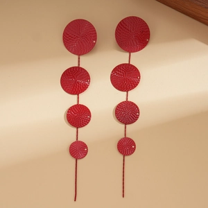 Detail of red tiered round earrings with hammer textured finish on beige background