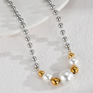 Detail of silver bead chain necklace with gradient white pearls on stone background