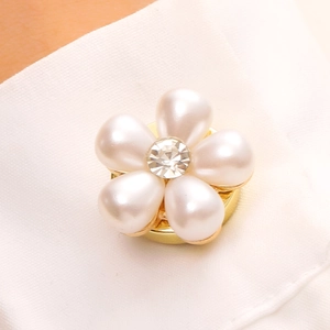 Détail d'un clip de chemise fleur avec cinq perles blanches et base dorée brillante