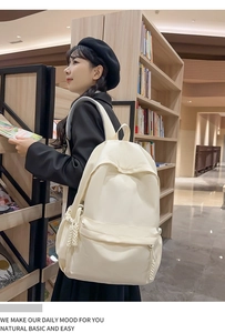 Cremeweißer Nylon-Schulrucksack mit gewebtem Anhänger-Detail in einer Bibliothek