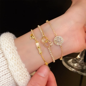 Detail showing layered gold plated clover and interlocking zircon bracelets on a wrist