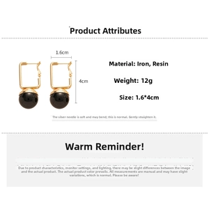 Detailed view of black resin ball earrings with golden frame and steel pins