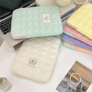 Macro view of heart-quilted fabric texture and secure zipper on the pastel laptop sleeve