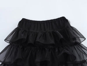 Dettaglio delle balze in rete nera e della fascia elastica in vita sulla minigonna