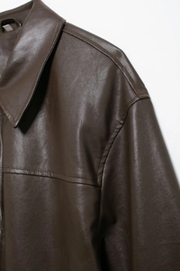 Close-up of fine faux leather texture and stitching on dark brown bomber jacket