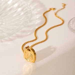 Macro detail of 18K gold plated stainless steel necklace with irregular relief pendant