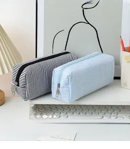 Close-up of textured seersucker pencil cases with stripes and smooth metal zippers