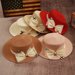 Detail of straw hats with chiffon bows and pearl accents in multiple colors on wood background