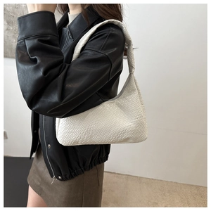 White woven hobo shoulder bag styled on a model wearing a black leather jacket