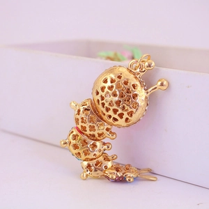 Detailed close-up of golden hollow caterpillar keychain with colorful rhinestones