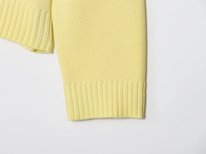 Detailed close-up of rib-knit cuffs on a vibrant yellow knitted cardigan jacket