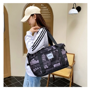 Detailed view of large newspaper print gym bag with purple straps held by a model