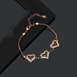 Detailed view of rose gold hollow heart bracelet with green gemstones and zircon pavé