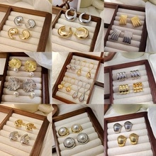 Variety of gold and silver alloy earrings with pearl accents on a wooden jewelry tray