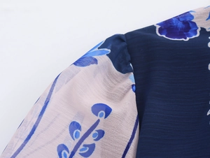 Detail of sheer chiffon sleeve with blue floral pattern and textured navy bodice