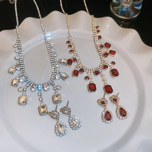 Detail view of silver and gold crystal jewelry sets with tassels on white plate