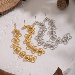Élégantes boucles d'oreilles trèfle à glands en or et argent sur fond de bois naturel