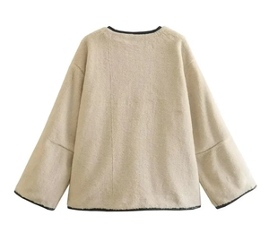 Détail du dos d'une veste en peluche beige avec liserés noirs et texture douce en fourrure