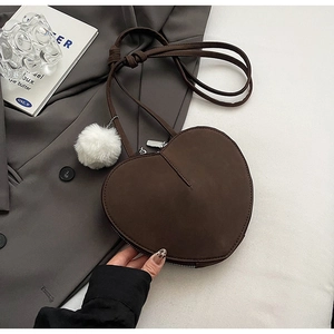Detailansicht der herzförmigen dunkelbraunen Wildledertasche mit weißem Pompon-Anhänger