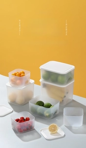Close-up of frosted food storage containers with white lids and fresh fruits inside