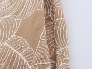 Detailed macro view of white embroidery patterns on breathable cotton-linen fabric texture