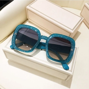 Detailed macro view of square glitter sunglasses on elegant white gift boxes