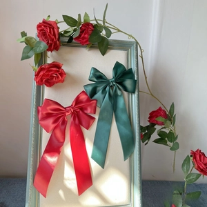 Detailansicht großer Satin-Haarschleifen in Rot und Grün mit eleganten langen Bändern