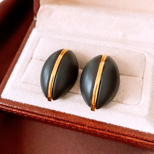 Detail shot of vintage black oval earrings with central gold stripe in a premium jewelry box