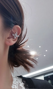 Close-up of silver cross ear cuff with sparkling marquise zircons worn on the ear